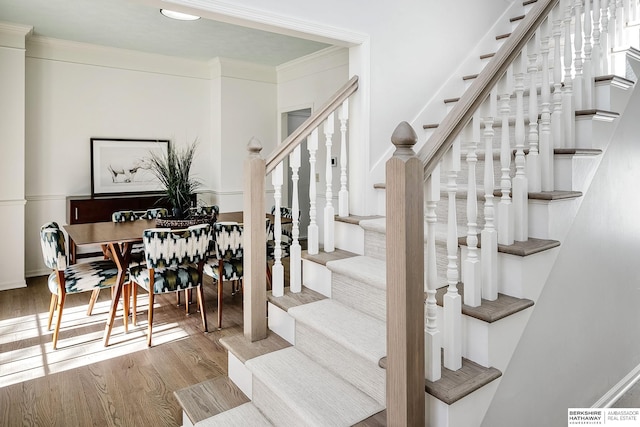 stairs featuring crown molding and hardwood / wood-style floors