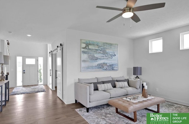 living room featuring a barn door, hardwood / wood-style flooring, and ceiling fan