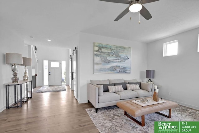 living room with a barn door, ceiling fan, and hardwood / wood-style floors