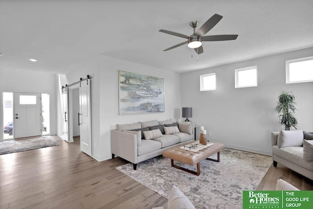 living room with hardwood / wood-style floors, a barn door, and ceiling fan