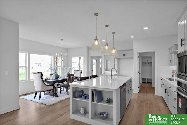 kitchen with white cabinets, a center island with sink, a healthy amount of sunlight, and light hardwood / wood-style floors