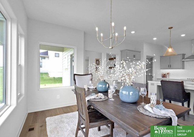 dining room with an inviting chandelier, a healthy amount of sunlight, and hardwood / wood-style flooring