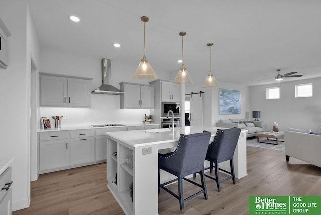11018 N 161st St, Bennington, NE 68007 - kitchen with wall chimney range hood, a barn door, a breakfast bar area, a sink, and a ceiling fan