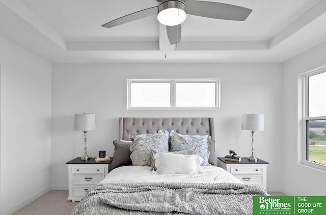 carpeted bedroom with a tray ceiling and ceiling fan