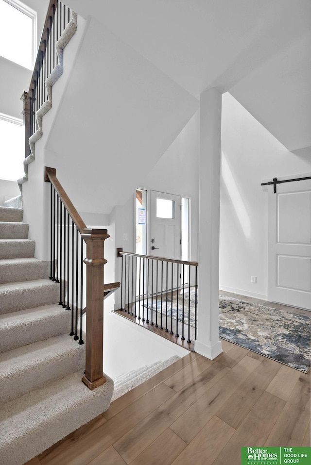 stairs with wood-type flooring, a barn door, and a high ceiling