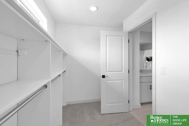 walk in closet with light colored carpet and sink