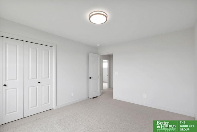 unfurnished bedroom with light colored carpet and a closet