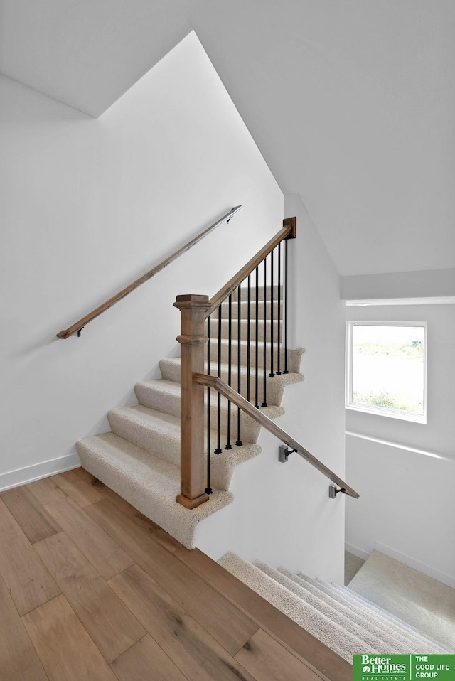 stairway with vaulted ceiling and hardwood / wood-style flooring