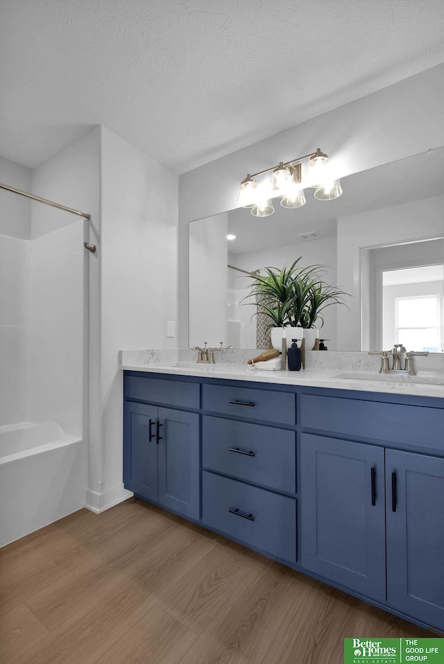 11018 N 161st St, Bennington, NE 68007 - bathroom with wood finished floors, double vanity, tub / shower combination, and a textured ceiling