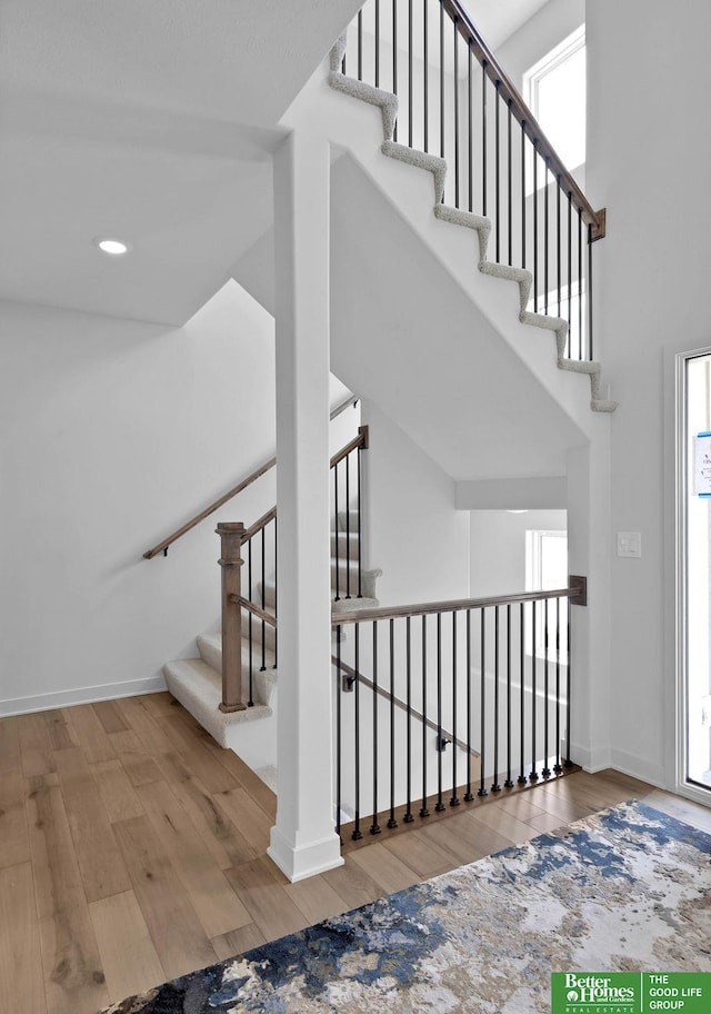 staircase with hardwood / wood-style floors and a high ceiling