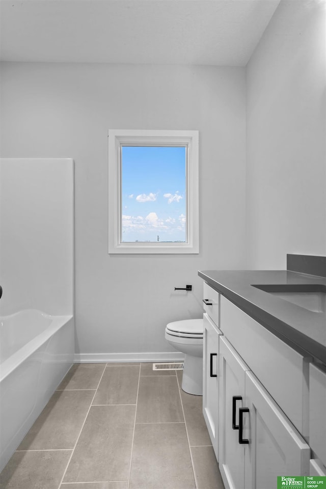 bathroom featuring tile patterned floors, vanity, toilet, and a bathing tub