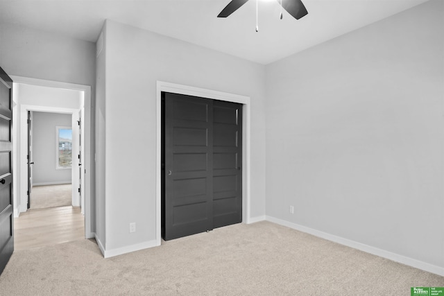 unfurnished bedroom featuring ceiling fan, a closet, and light colored carpet