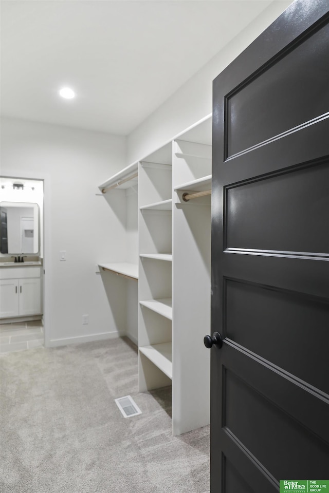 walk in closet featuring light carpet