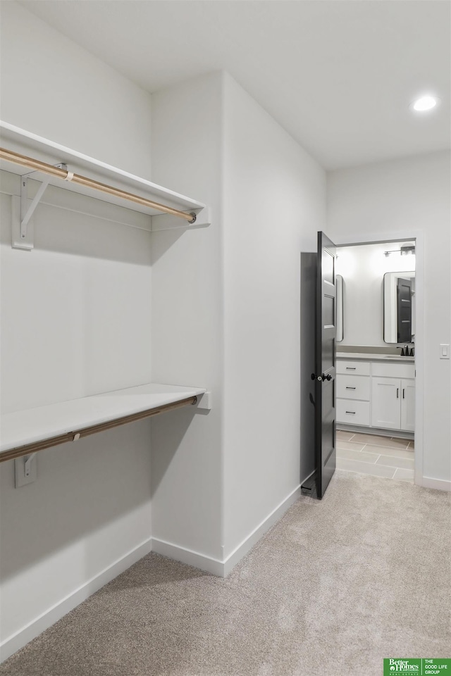 spacious closet with light carpet and sink