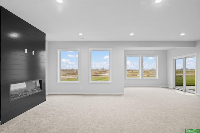 unfurnished living room featuring light carpet, a fireplace, and wooden walls