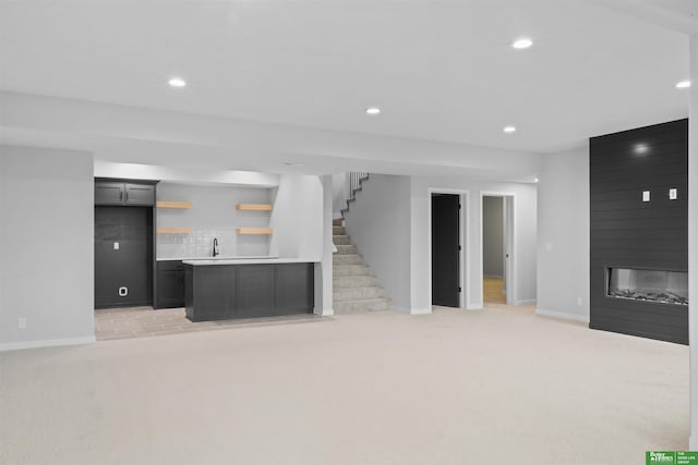 unfurnished living room featuring light carpet, a fireplace, and sink