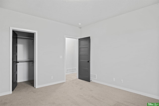 unfurnished bedroom featuring light carpet, a walk in closet, and a closet