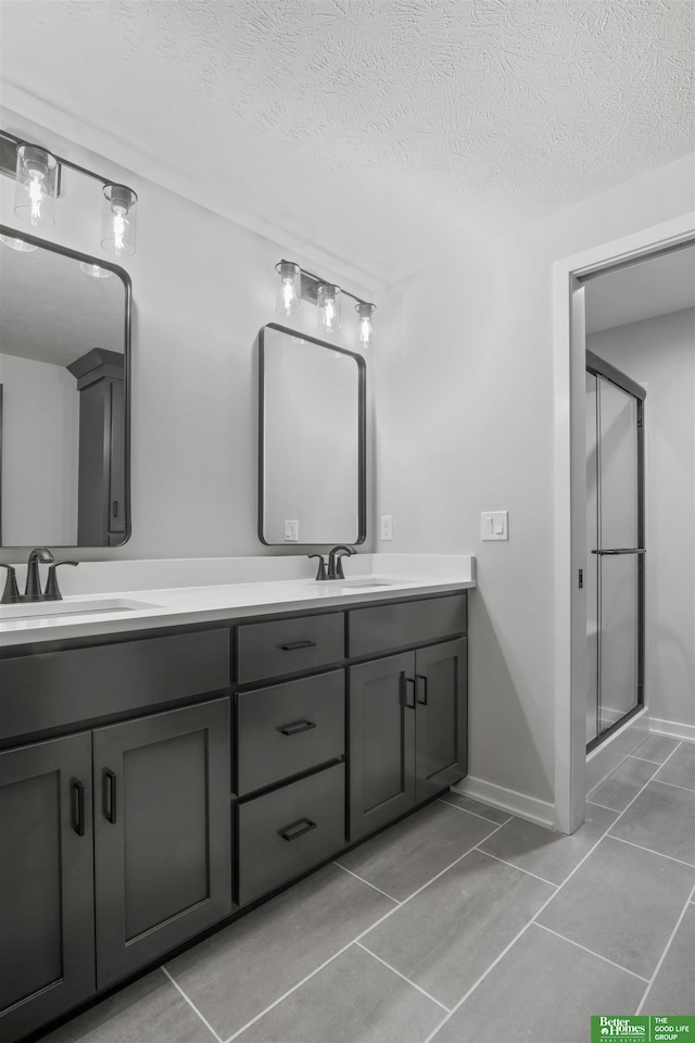 bathroom with vanity, a textured ceiling, tile patterned floors, and a shower with shower door