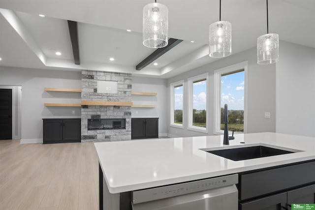 kitchen featuring dishwasher, sink, an island with sink, decorative light fixtures, and light hardwood / wood-style floors