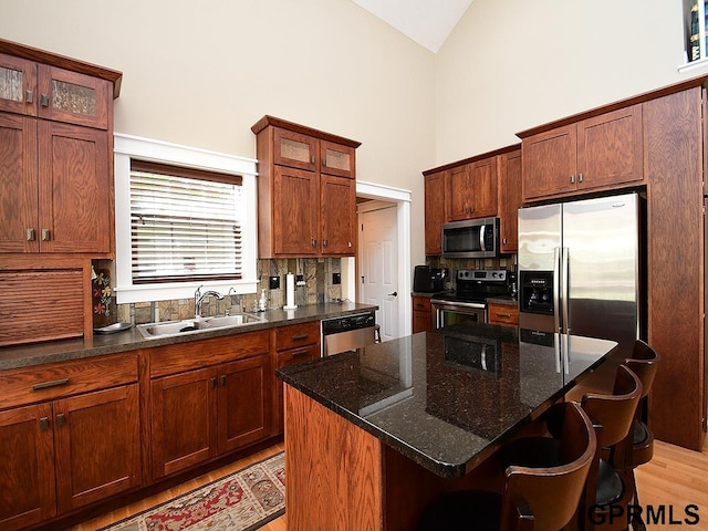 kitchen featuring a center island, sink, light hardwood / wood-style flooring, appliances with stainless steel finishes, and a kitchen bar