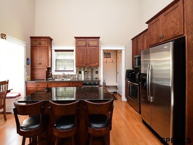 kitchen featuring a breakfast bar, a kitchen island, light wood-type flooring, and appliances with stainless steel finishes