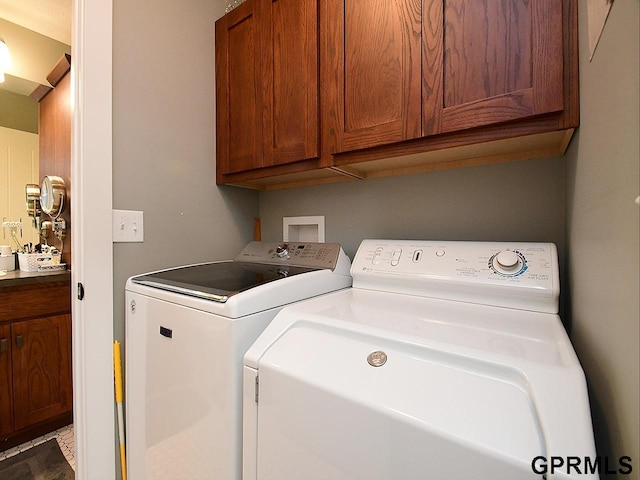 clothes washing area with washer and dryer and cabinets