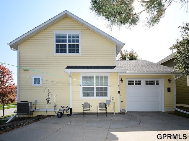 rear view of property with central air condition unit and a garage