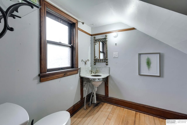 bathroom featuring toilet, wood-type flooring, and vaulted ceiling