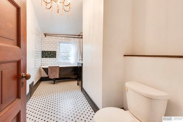 bathroom with tile patterned floors, toilet, and a chandelier