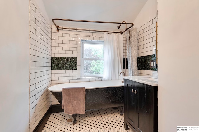 bathroom featuring tile patterned floors, vanity, tile walls, and vaulted ceiling