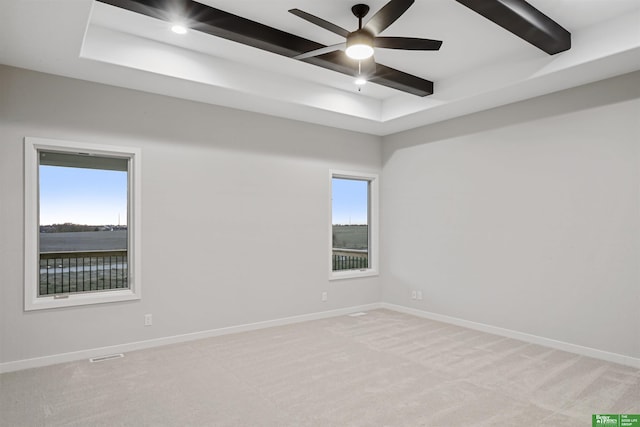 carpeted empty room with a wealth of natural light, beamed ceiling, a water view, and ceiling fan