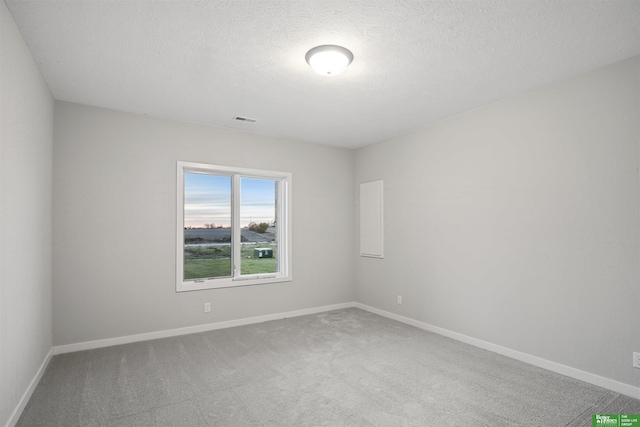 carpeted empty room with a textured ceiling