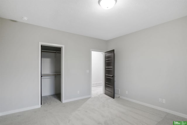 unfurnished bedroom featuring light colored carpet, a spacious closet, and a closet