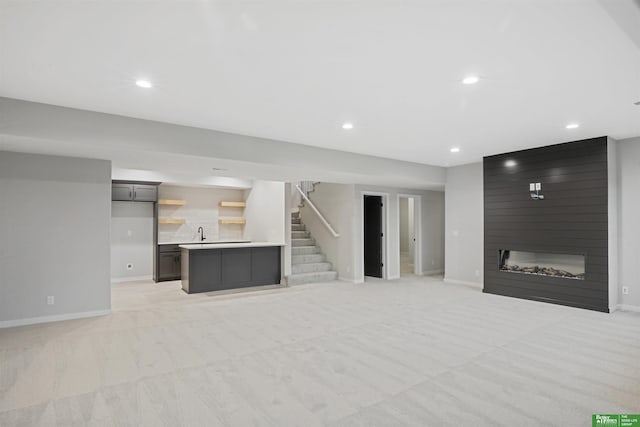 living room with a large fireplace, light colored carpet, and sink