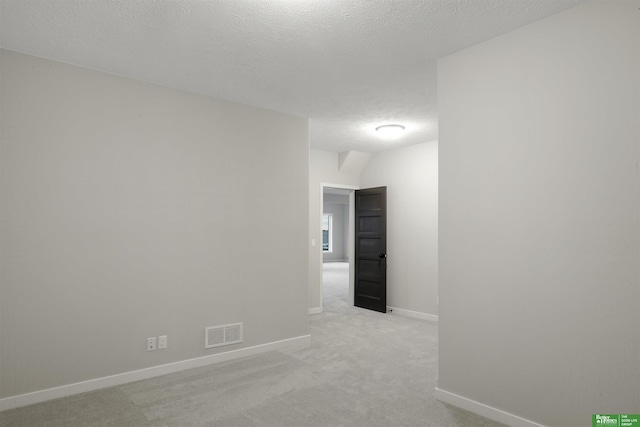 spare room with light carpet and a textured ceiling