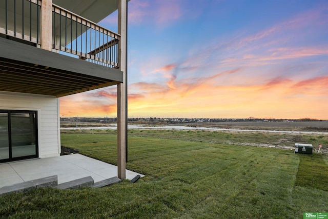 yard at dusk with a deck with water view and a patio