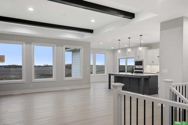 kitchen featuring plenty of natural light, white cabinets, decorative light fixtures, and light wood-type flooring