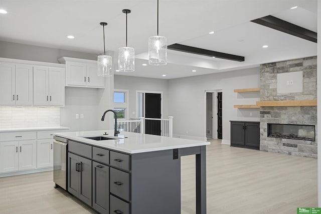 kitchen with stainless steel dishwasher, gray cabinetry, pendant lighting, white cabinets, and light hardwood / wood-style floors