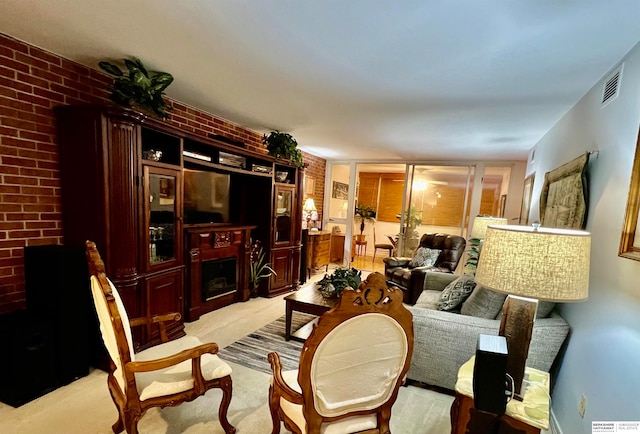 living room featuring a fireplace, light colored carpet, and brick wall