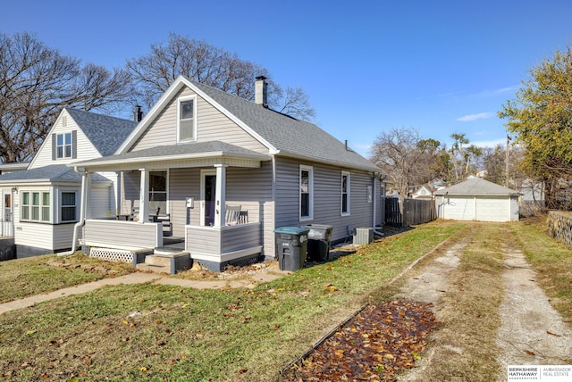 view of front of home with a front yard, a porch, an outdoor structure, and central air condition unit