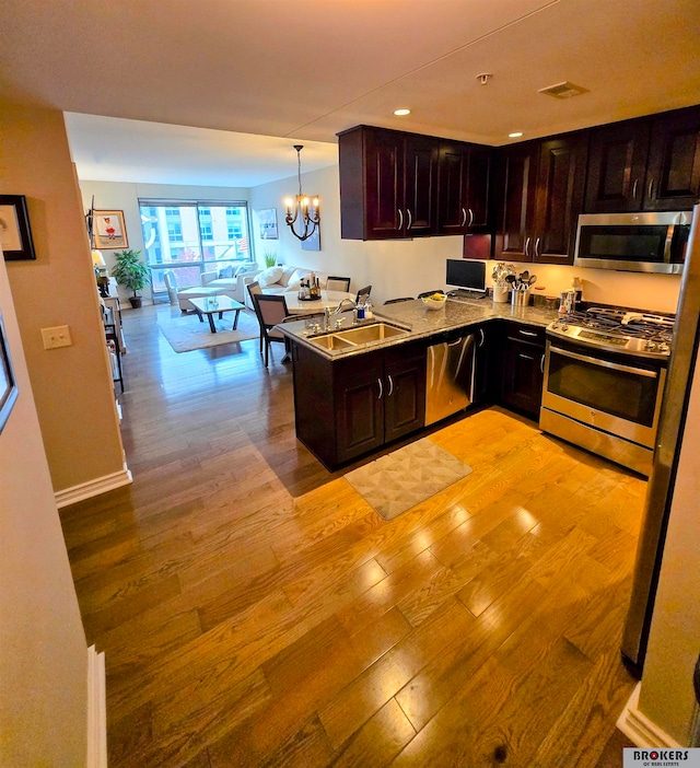 kitchen featuring sink, hanging light fixtures, stainless steel appliances, kitchen peninsula, and light hardwood / wood-style floors