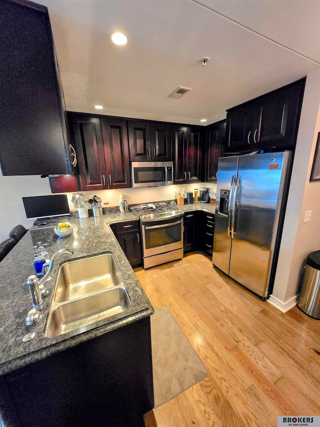 kitchen with appliances with stainless steel finishes, light wood-type flooring, and sink