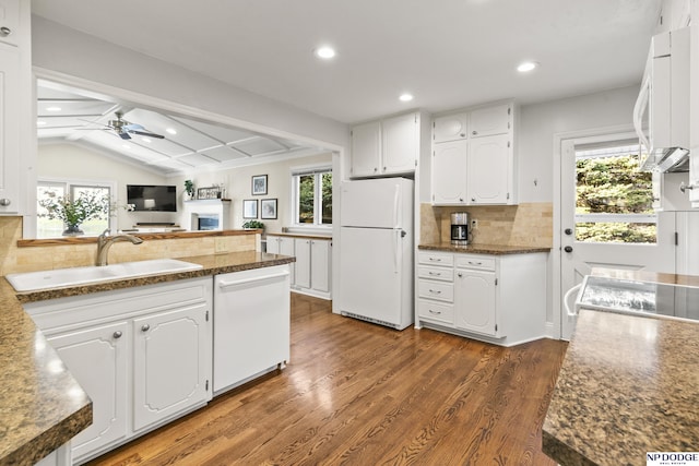 kitchen with dark hardwood / wood-style flooring, white appliances, vaulted ceiling, sink, and white cabinets