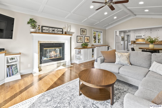 living room featuring a tiled fireplace, ceiling fan, and light hardwood / wood-style flooring