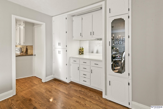 bar with white cabinets and dark hardwood / wood-style floors