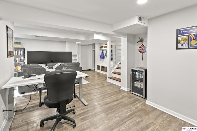 office with built in shelves, hardwood / wood-style flooring, and wine cooler