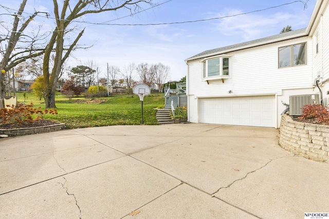 view of side of property featuring a yard, central AC, and a garage