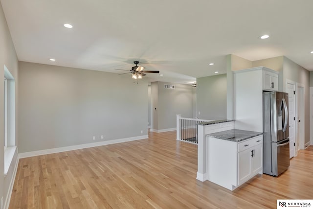 kitchen featuring dark stone counters, ceiling fan, light wood-type flooring, white cabinetry, and stainless steel refrigerator