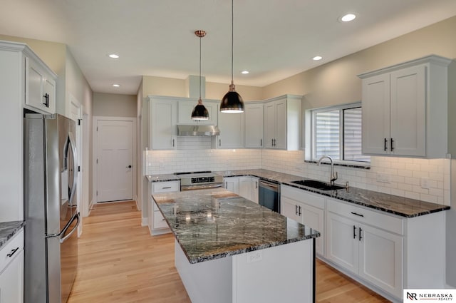 kitchen with sink, hanging light fixtures, stainless steel appliances, a kitchen island, and white cabinets