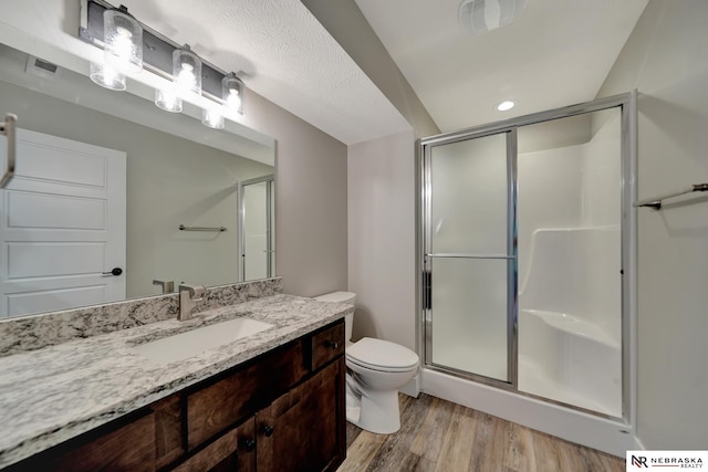 bathroom with toilet, vanity, a shower with shower door, and hardwood / wood-style flooring